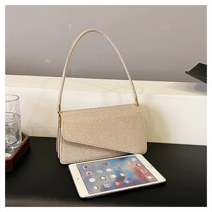 Détail du sac de soirée à paillettes dorées avec rabat asymétrique en forme d'enveloppe