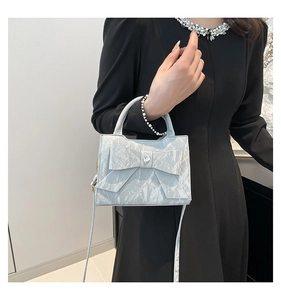 Détail du sac à nœud bleu-gris avec texture plissée et ornement en diamant de cœur