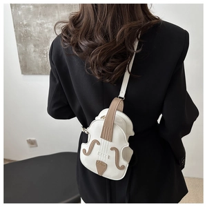 Chic violin shaped crossbody bag in white PU leather shown on a black suit shoulder