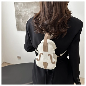 Detail of creative violin-shaped crossbody bag in cream white faux leather worn by model