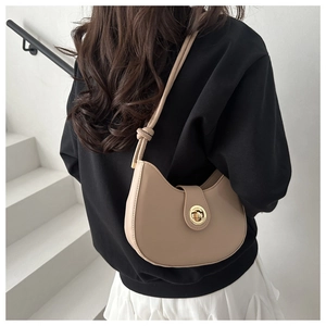 Detailed side view of a beige crescent bag featuring a golden ring clasp and knotted strap