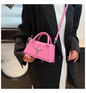 Détail d'un sac à main rose avec étoile argentée porté sur une tenue noir et blanc