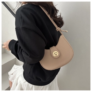 Detail of beige faux leather underarm bag featuring a golden circular twist lock closure