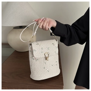 Close-up of woven shoulder bag with floral embroidery and golden metallic clasp detail