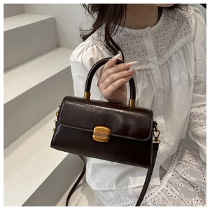 Detail of dark brown vintage faux leather handbag with gold metal clasp and top handle