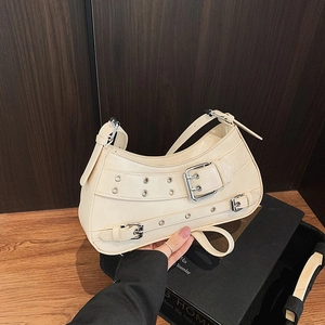 Chic off-white half-moon shoulder bag with punk silver metal eyelets and buckled straps