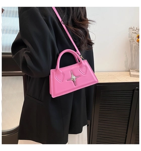 Gros plan du sac bandoulière en cuir rose vif avec boucle étoile argentée sur mannequin