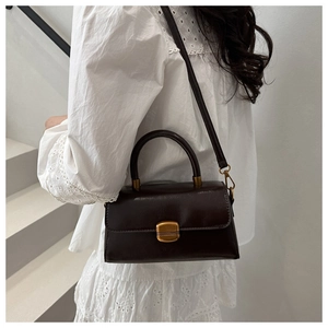 Model wearing dark chocolate PU leather crossbody bag with gold buckle detail