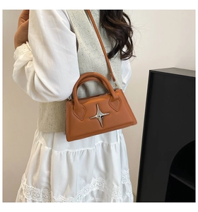 Sac à main carré marron orangé avec boucle étoile argentée porté avec robe blanche