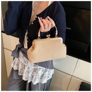 Detail of light beige woven texture bag with gold kiss-lock closure and elegant chain