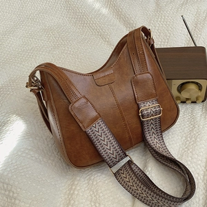 Vintage brown leather hobo bucket bag with a stylish ethnic woven wide shoulder strap