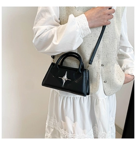 Détail du sac bandoulière noir avec emblème étoile porté par un mannequin