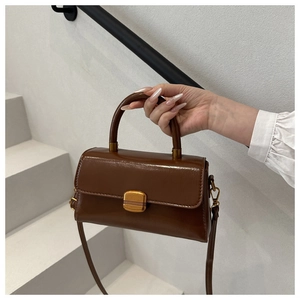 Close-up of vintage brown leather handbag with gold metal clasp and top handle details