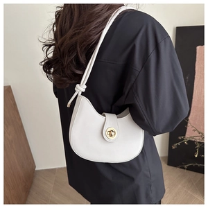 Detail of white crescent shoulder bag featuring gold twist lock and knotted strap design