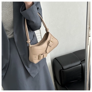 Detail of beige underarm bag with decorative leather straps and vintage buckles