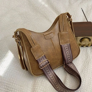 Retro caramel brown bucket bag with geometric woven wide strap on a vintage surface