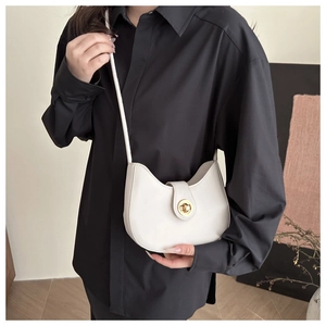 Fashionable beige crescent leather shoulder bag with gold metal clasp on model