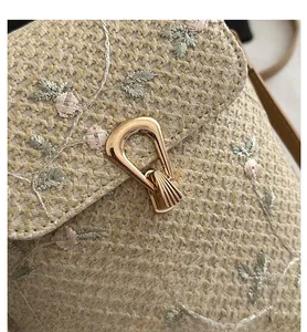 Detail of woven straw bag featuring delicate floral embroidery and a golden shell-shaped lock