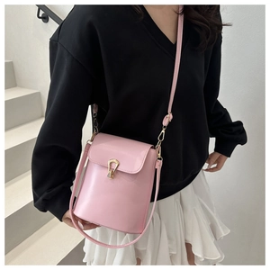 Sac seau en cuir PU rose avec fermoir doré en forme de goutte porté par un modèle