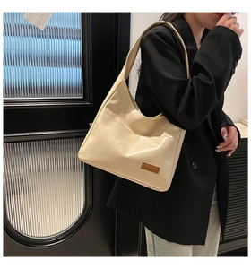 Detail view of the beige faux leather hobo tote bag with a brown decorative brand tag