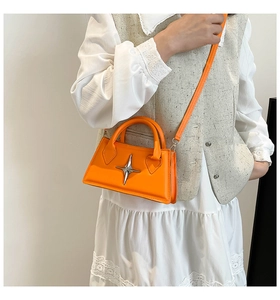 Mini sac bandoulière orange avec logo étoile argentée porté par un mannequin en décor épuré