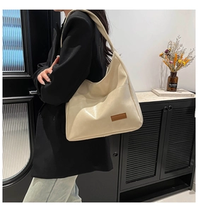 Close-up of a large beige faux leather hobo shoulder bag with a brown decorative patch