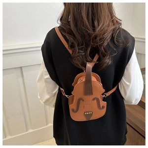 Detail view of a creative violin shaped crossbody bag in dark brown leather worn by a model