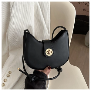 Detail of black saddle bag with matte leather and golden swivel lock on a chair