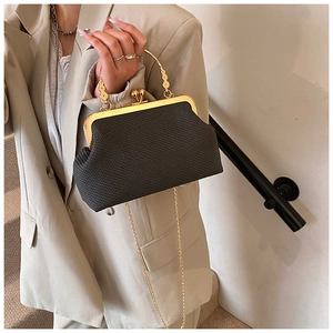 Detail of a black woven evening clutch featuring a wavy gold handle and metal chain
