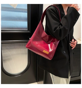 Detail of burgundy leather hobo bag with contrast decorative label and precise stitching