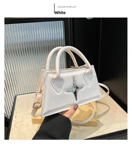 Détail d'un sac à main blanc en similicuir avec emblème étoile argentée et bandoulière