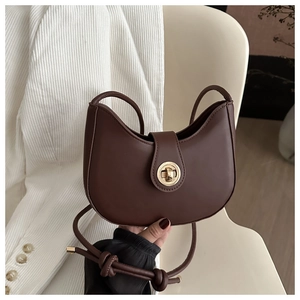 Detail view of a dark brown crescent bag with a gold twist lock and cord strap