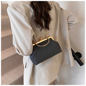Detail of vintage frame bag with gold clasp and chain strap worn with beige suit