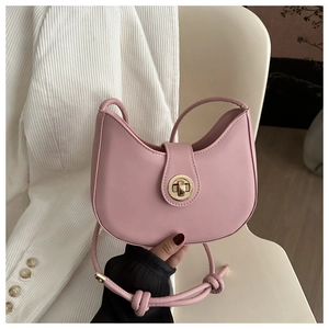 Detail of pink crescent moon bag featuring a circular gold metal twist lock and knot strap