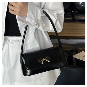 Détail du sac à bandoulière en cuir verni noir brillant avec boucle noeud doré