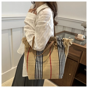 Detail of woven tote bag with fringe edge, striped pattern and leather shoulder strap