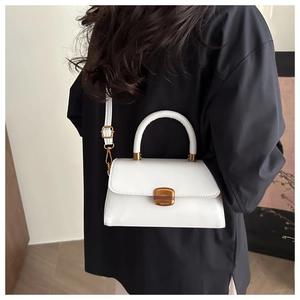 Detail of white leather handbag with gold buckle and adjustable shoulder strap on model
