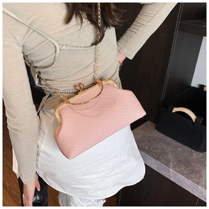 Detail of light pink woven clutch with gold clasp and chain strap on a model