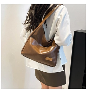 Detail of the large brown hobo tote bag with glossy finish and wide shoulder strap