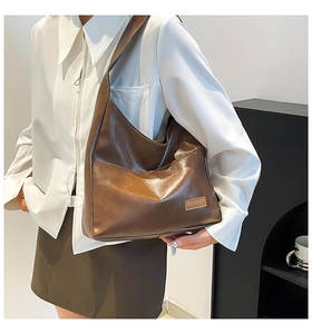 Detail view of large dark brown leather tote bag with soft texture and wide shoulder strap
