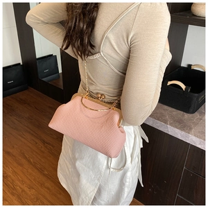 Detailed view of pink woven bag featuring gold clasp and metal chain on a model