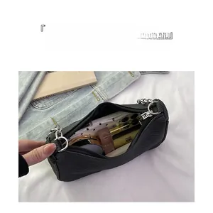 Detail showing the storage capacity of a black faux-leather shoulder bag with silver chain