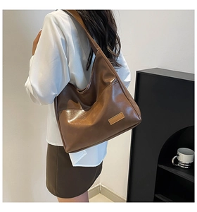 Detailed close-up of brown vintage leather tote bag with wide strap on model's shoulder