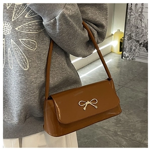 Détail d'un sac baguette en cuir glacé marron avec boucle nœud dorée et fine bandoulière