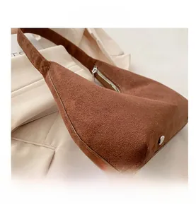 Gros plan d'un sac hobo en daim marron avec fermeture éclair argentée et rivet métallique