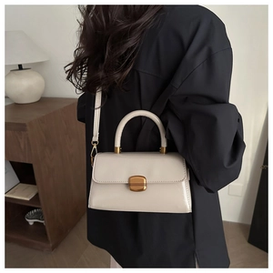 Close-up of cream square handbag showing gold vintage buckle and fine stitching details