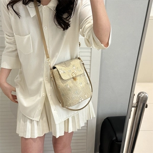 Woven crossbody bag with floral embroidery and gold metal clasp worn by a model