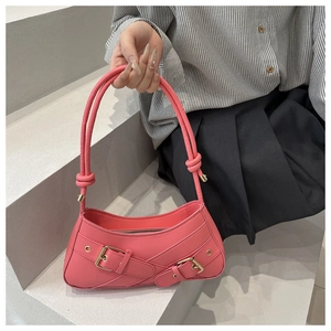 Detailed shot of pink faux leather handbag with unique cross buckle straps and tubed handles