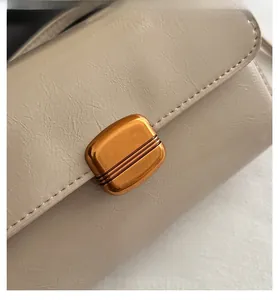 Detailed macro view of beige lychee leather texture and bronze metal lock on the handbag