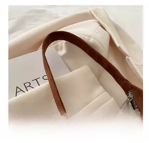 Gros plan d'un sac à main en daim marron avec fermeture éclair argentée sur tissu beige